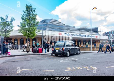 Ein schwarzes Taxi holt die Passagiere am Taxistand vor dem Bahnhof Reading in Berkshire, Großbritannien, ab Stockfoto