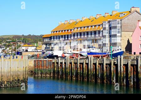 Boote im Trockendock am Rand des Hafens mit Wohnungen am Heck, West Bay, Dorset, UK, Europa, Oktober. Stockfoto