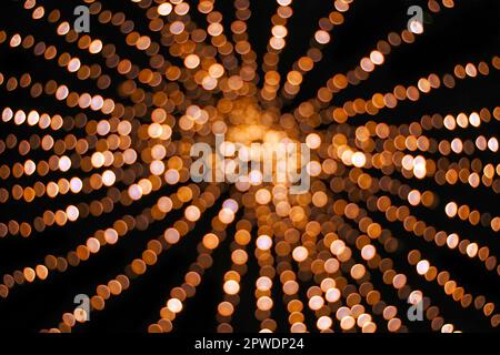 Abstrakte gelbe und orangefarbene Weihnachts-Bokeh-Bälle und helle, unscharfe Bokeh-Lichter auf schwarzem Hintergrund Stockfoto