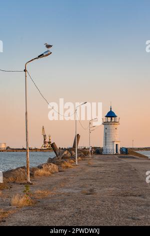 Aus nächster Nähe sehen Sie den Leuchtturm von Genua mit einem blauen Dach, vom Pier aus Felsen, in einem Hafen am Schwarzen Meer. Stockfoto