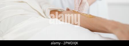 Frau mit Haarentfernung Verfahren am Arm mit Zuckerpaste im Schönheitssalon, Nahaufnahme Stockfoto