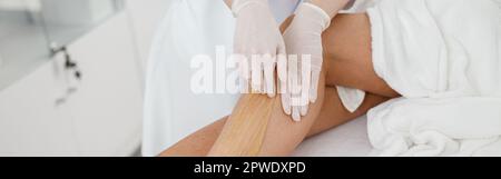 Frau Client mit Haarentfernung Verfahren auf Bein mit Zuckerpaste im Schönheitssalon Stockfoto