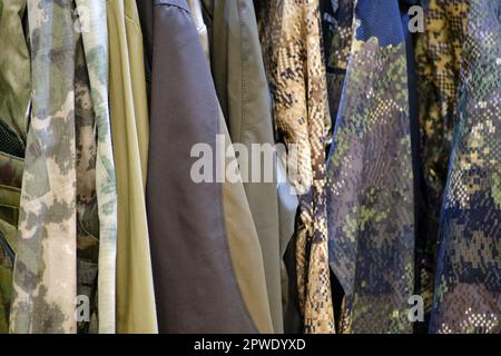 Armeekleidung an einem Kleiderbügel in einem Militärwarenladen Armeekleidung an einem Kleiderbügel in einem Militärwarenladen Stockfoto