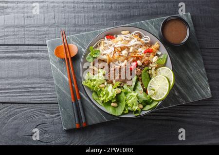 Pho Bo Tron vietnamesischer Rinderreis Nudeln Salat in einer Schüssel auf einem Holztisch. Horizontale Draufsicht von oben Stockfoto