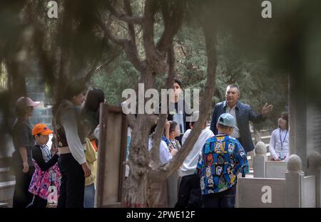 (230430) -- YECHENG, 30. April 2023 (Xinhua) -- Eniwar Emer (R, hinten) erzählt den Besuchern Geschichten über die Märtyrer auf dem Yecheng-Märtyrerfriedhof in Yecheng, Nordwestchina der Autonomen Region Xinjiang Uygur, 16. April 2023. Jeden April blühen Blumen auf dem Friedhof der Yecheng-Märtyrer in der Autonomen Region Xinjiang Uygur im Nordwesten Chinas, wo 233 Märtyrer begraben wurden. „Ich werde mich gut um den Friedhof kümmern“, sagte der 53-jährige Eniwar Emer vor dem Grabstein seines Vaters. Eniwar ist ein Hüter der zweiten Generation auf dem Friedhof der Yecheng-Märtyrer und folgt den Spuren seines Vaters Emer Stockfoto