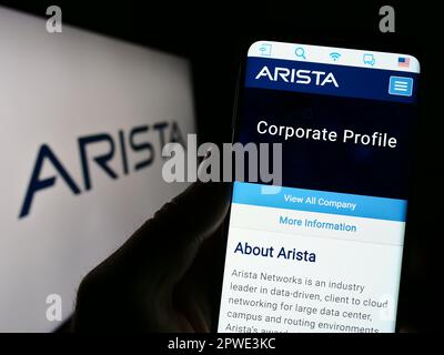 Person, die ein Mobiltelefon mit einer Webseite des Computernetzwerkunternehmens Arista Networks Inc. Auf dem Bildschirm mit Logo hält. Konzentrieren Sie sich auf die Mitte des Telefondisplays. Stockfoto