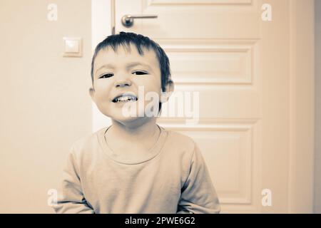 Das kleine Baby wimmert und ist unartig. Das kleine Kind weint und leidet im Wohnzimmer. Ein Kind im Alter von einem Jahr, neun Monaten Stockfoto