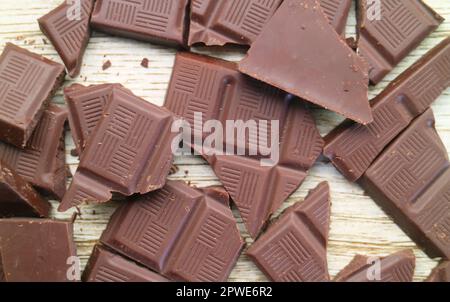 Ein Haufen zerbrochener dunkler Schokoladenstücke auf Holzhintergrund Stockfoto