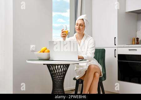 Eine junge Frau im Bademantel, die beim Frühstück ihre Post abfragt Stockfoto