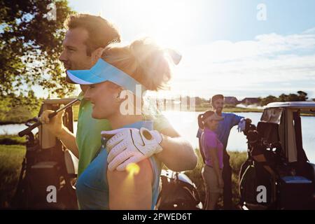 Liebe füreinander und zum Spiel teilen. Zwei Paare, die an einem sonnigen Tag eine Runde Golf spielen. Stockfoto