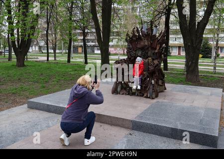 Die Frau eines ukrainischen Soldaten wird dabei gesehen, wie sie ein Foto ihrer Tochter am Eisernen Thron des Ostens im Zentrum von Zaporischschien macht. Der Eiserne Thron des Ostens in Zaporischzhien, Ukraine, der aus echten militärischen Maschinen, Trümmern und Granaten besteht. Er wurde im Winter 2016 an den Positionen der Streitkräfte der Ukraine in der Stadt Avdiivka in der Region Donezk hergestellt. Der Eiserne Thron des Ostens wurde in der Stadt Zaporischhien mit Unterstützung von örtlichen Hilfssheriffs errichtet - Kriegsveteranen. Er würdigt den herausragenden Willen des ukrainischen Volkes, zu gewinnen. Die Autoren dieser Metallskulptur wurden von inspiriert Stockfoto