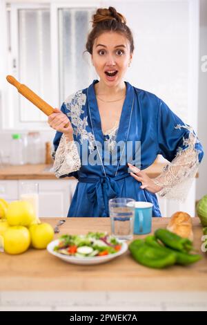 Wütend Frau schreiend und winkend Nudelholz in der Küche zu Hause Stockfoto