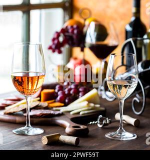 Rosen-, Weiß- und Rotwein serviert mit Wurstplatte, bereit zum Teilen. Stockfoto