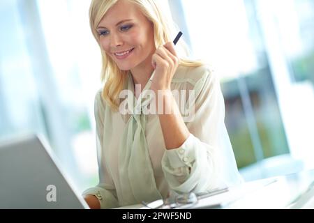 Firmenschönheit. Eine lächelnde Geschäftsfrau, die an ihrem Laptop arbeitet. Stockfoto