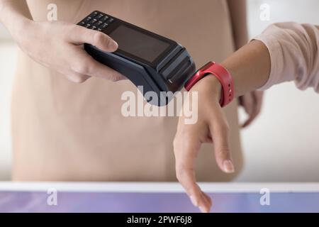 Eine Frau hält ihre moderne Smartwatch gegen einen kontaktlosen Zahlungsterminalautomaten Stockfoto