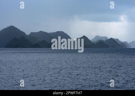 In Misool, Raja Ampat, Indonesien, treibt ein Regensturm über abgelegene Kalksteininseln. Diese tropische Region ist für ihre hohe Artenvielfalt bekannt. Stockfoto