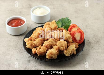 Hausgemachtes Hühnchen-Popcorn mit Chilisauce und Mayonaise. Hähnchenbeschichtung mit Mehl und frittiertem Stockfoto