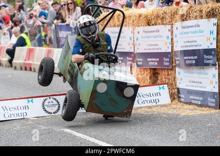 Großer Dunmow, Essex, Großbritannien. April 2023 30. Rund sechzig Teams haben am vierten Great Dunmow Soapbox Race teilgenommen. Die unmotorisierten Wagen der Teams werden von der Startlinie über Sprünge bis zu einem zeitgesteuerten Ziel geschoben. Die Wagen variieren von einfachen bis hin zu aufwändigeren. Hilfe für Heldenwagen mit fehlendem Rad Stockfoto