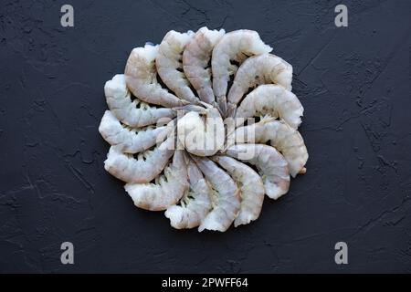 Frische Vannamei-Garnelen ohne Kopf für die Zubereitung der Mahlzeit. Rohe ungekochte asiatische Tigergarnelen. Pazifische weiße Garnelen oder Königsgarnele auf schwarzem Hintergrund Stockfoto