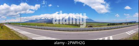 fahren sie durch die slowakische Landschaft und genießen Sie einen malerischen Blick auf die wunderschöne tatra. Die Straße führt durch ein riesiges Ackerland und bietet eine Stockfoto