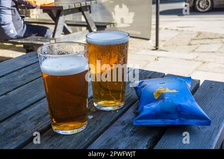 19.04.023 Lancaster, Lancashire, Vereinigtes Königreich. Ein Bier und ein Päckchen Chips vor einer Kneipe trinken Stockfoto