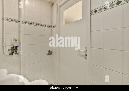 Ein Badezimmer mit weißen Fliesen und grünen Zierleisten rund um