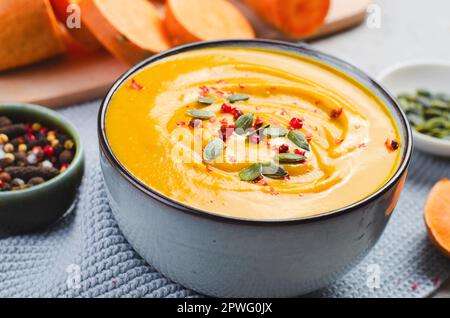 Süße Kartoffelsuppe, leckerer hausgemachter Kürbis, Süßkartoffel, Karottensuppe in einer Schüssel auf hellem Hintergrund Stockfoto