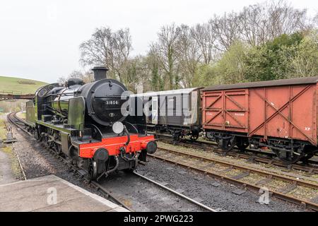Dampflokomotive, die an der Norden Station ankommt, vorbei an Old Goods Waggons der Swanage Steam Heritage Railway, Dorset, England Stockfoto
