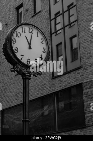 Ein atemberaubendes Schwarz-Weiß-Foto einer Wanduhr in Bielsko Biala Polen mit seinem prachtvollen Gesicht vor dem architektonischen Äußeren eines imposanten Bu Stockfoto