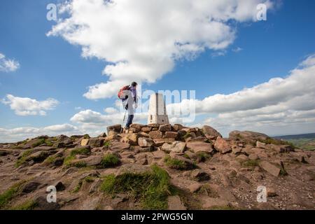Mann am Berg trig Point, der im Peak District National Park auf den Roaches Range of Rocks in den Staffordshire Moorlands Leek Staffordshire spazierengeht Stockfoto