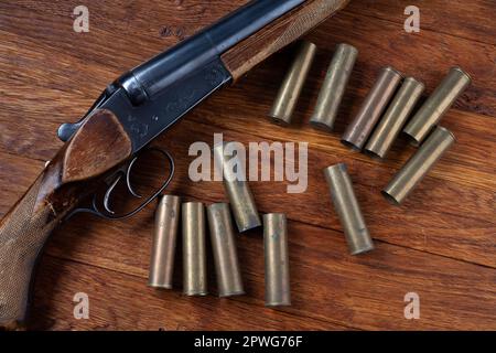 Antike 16-Gauge Break-Action glatt gebohrte Schrotflinte mit Patronen. Auf Holztisch. Stockfoto