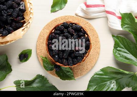 Korb aus Korb mit leckeren reifen schwarzen Maulbeeren auf weißem Tisch, flach liegend Stockfoto