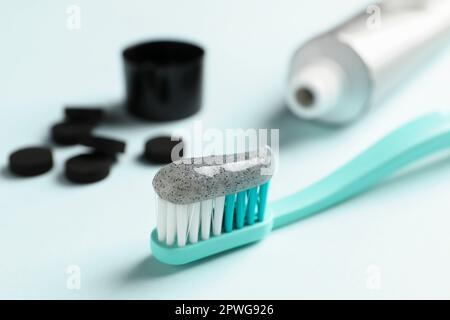 Bürsten Sie mit Holzkohle-Zahnpasta auf hellem Hintergrund, Nahaufnahme Stockfoto