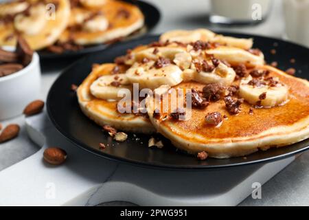 Leckere Pfannkuchen mit Bananenscheiben, serviert auf dem Tisch, Nahaufnahme Stockfoto