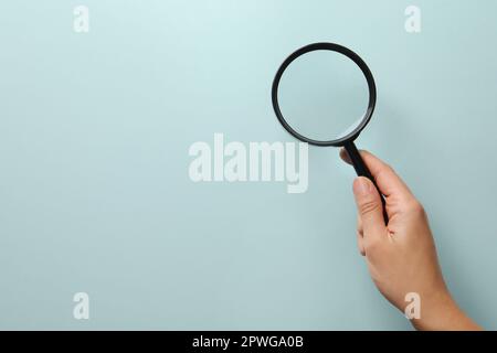 Frau mit Lupe auf hellblauem Hintergrund, Nahaufnahme mit Platz für Text. Mikroben-Konzept Stockfoto