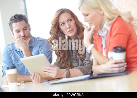 Die Haare meiner Kollegen sehen toll aus. Eine Gruppe von drei Kollegen, die sich gemeinsam ein digitales Tablet ansehen. Stockfoto