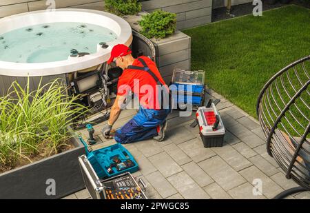 Wartung des Wannen-Whirlpools für kleine Wohnungen durch einen weißen SPA-Techniker. Stockfoto