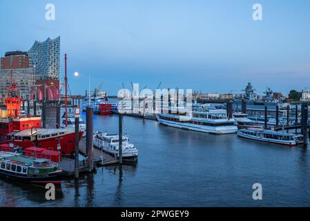 Hamburg, Deutschland - 05 15 2022: Blick auf den hamburger Hafen mit verschiedenen Schiffen und die elbphilharmonie am Abend bei Vollmond. Stockfoto