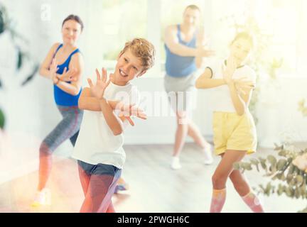 Ein glücklicher Junge, der mit seiner Familie Tanzbewegungen praktiziert Stockfoto