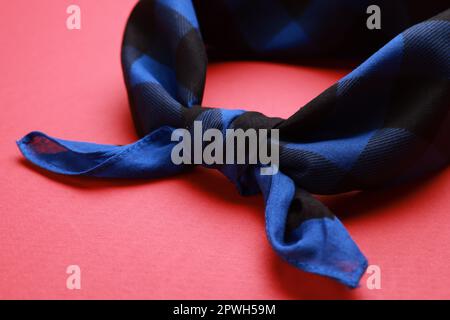 Gefliestes blaues Bandana mit Karomuster auf rotem Hintergrund, Nahaufnahme Stockfoto