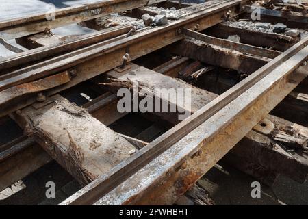 Selektiver Fokus und Details des Abbruchs von rustikalen Bahngleisen auf alten Eisenbahnschwellen aus recyceltem Holz. Stockfoto