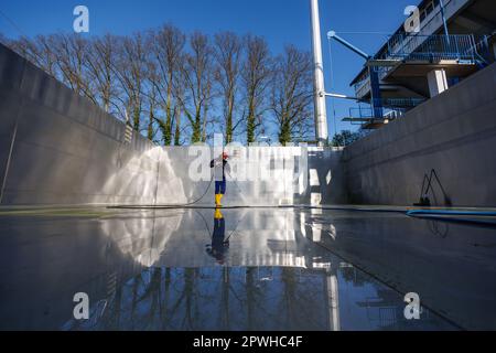 26. April 2023, Bayern, Nürnberg: Michael, Schichtleiter und Poolwächter im Stadionbad, entfernt wetterbedingte Verschmutzungen wie Algen oder Blätter während der Reinigungsarbeiten aus dem leeren Tauchbecken im Stadionbad, um sich auf die Outdoor-Poolsaison 2023 vorzubereiten. Je nach Wetterlage werden die ersten Außenpools voraussichtlich Anfang Mai eröffnet, andere folgen nach Angaben mehrerer bayerischer Städte und kommunaler Poolbetreiber Mitte des Monats. Die Eintrittspreise bleiben an vielen Stellen stabil, aber viele Poolbetreiber beschweren sich über Personalmangel Stockfoto