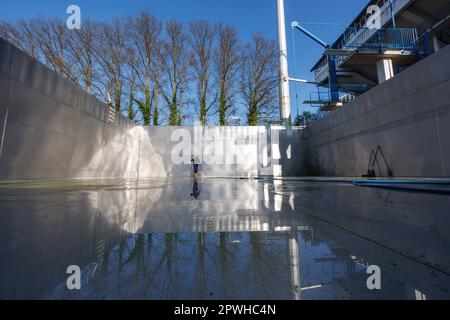 26. April 2023, Bayern, Nürnberg: Michael, Schichtleiter und Poolwächter im Stadionbad, entfernt wetterbedingte Verschmutzungen wie Algen oder Blätter während der Reinigungsarbeiten aus dem leeren Tauchbecken im Stadionbad, um sich auf die Outdoor-Poolsaison 2023 vorzubereiten. Je nach Wetterlage werden die ersten Außenpools voraussichtlich Anfang Mai eröffnet, andere folgen nach Angaben mehrerer bayerischer Städte und kommunaler Poolbetreiber Mitte des Monats. Die Eintrittspreise bleiben an vielen Stellen stabil, aber viele Poolbetreiber beschweren sich über Personalmangel Stockfoto