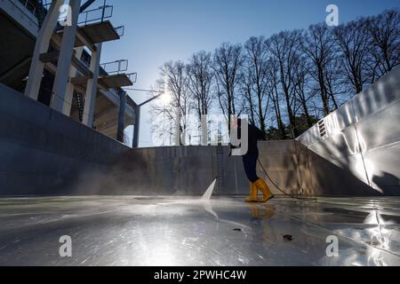 26. April 2023, Bayern, Nürnberg: Michael, Schichtleiter und Poolwächter im Stadionbad, entfernt wetterbedingte Verschmutzungen wie Algen oder Blätter während der Reinigungsarbeiten aus dem leeren Tauchbecken im Stadionbad, um sich auf die Outdoor-Poolsaison 2023 vorzubereiten. Je nach Wetterlage werden die ersten Außenpools voraussichtlich Anfang Mai eröffnet, andere folgen nach Angaben mehrerer bayerischer Städte und kommunaler Poolbetreiber Mitte des Monats. Die Eintrittspreise bleiben an vielen Stellen stabil, aber viele Poolbetreiber beschweren sich über Personalmangel Stockfoto