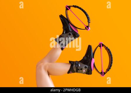 Känguru-Sprungschuhe für Fitness mit pinkfarbenen Akzenten auf orangefarbenem Hintergrund. Sportbeine für Damen. Stockfoto