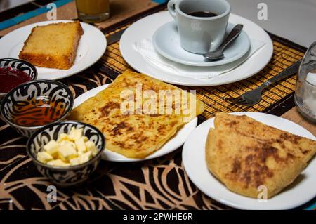 Traditionelles marokkanisches Frühstück mit Pfannkuchen, Kaffee, Brot, Butter, Honig und Marmelade auf dem Esstisch Stockfoto