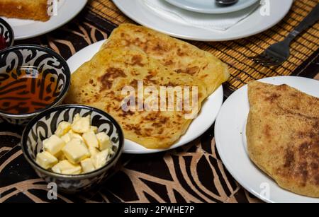 Traditionelles marokkanisches Frühstück mit Pfannkuchen, Brot, Butter und Honig auf dem Esstisch Stockfoto