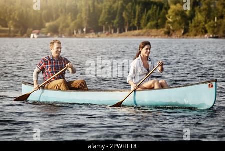 Kanufahren ist sogar noch besser, wenn man es gemeinsam nutzt. Ein junges Paar, das eine Kanufahrt auf dem See macht. Stockfoto