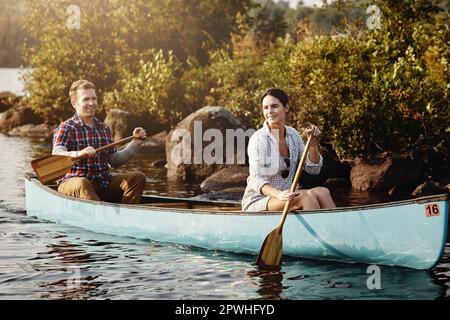 Es ist schwer, nicht glücklich zu sein, wenn man mit dem Kajak unterwegs ist. Ein junges Paar, das eine Kanufahrt auf dem See macht. Stockfoto
