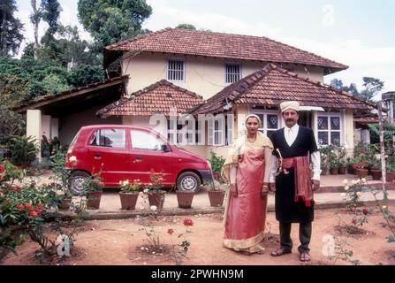 Kodava-Paar in einem traditionellen Haus vor ihrem Haus, Kodagu Coorg, Karnataka, Indien Stockfoto